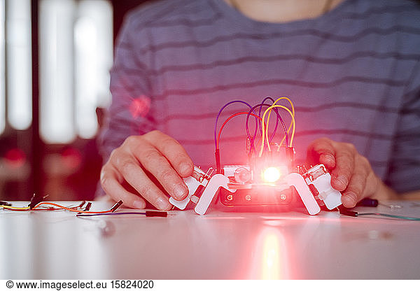 Boy's hand assembling robot  red light