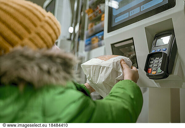 Boy scanning package with bar code reader in store