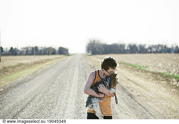 Boy showing his friendship with his dog in a countryside setting.