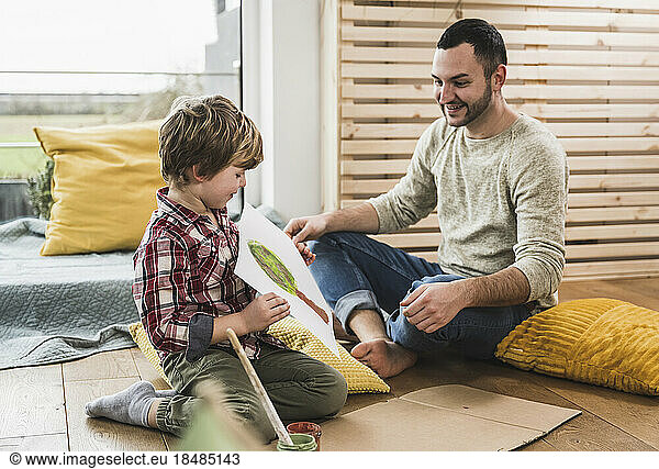 Boy showing his painting to father at home