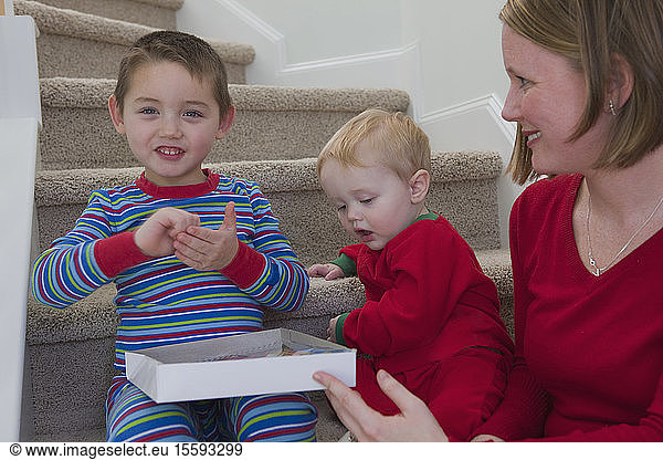 Boy signing the word 'Write' in American Sign Language sitting with his brother and mother