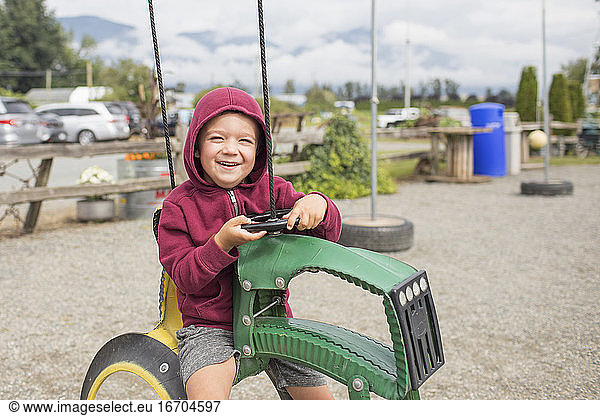boy sits on play ride on tractor at farm made from recycled tires