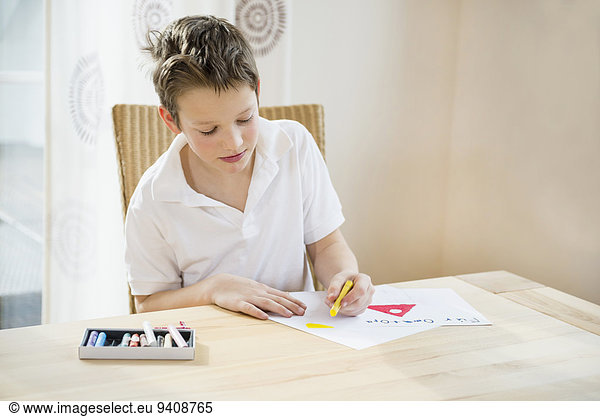 Boy sitting at table painting a picture