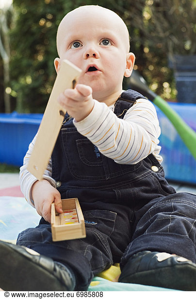 Boy Sitting in Backyard  Playing with Wooden Building Blocks