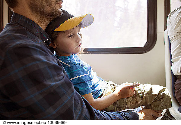 Boy sitting on father while travelling in train