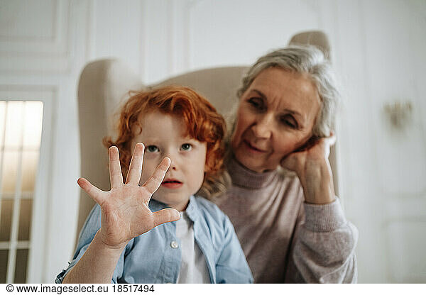 Boy sitting with grandmother gesturing at home