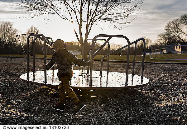 Boy spinning merry-go-round at playground