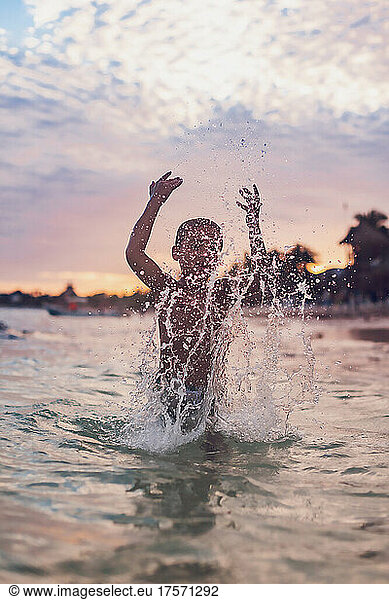 Boy splashing water at the beach.