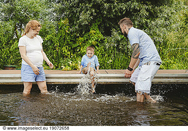 Boy splashing water with parents enjoying in lake