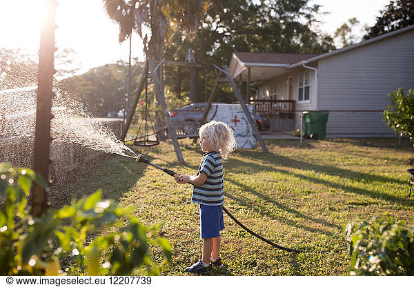Boy spraying water from hosepipe