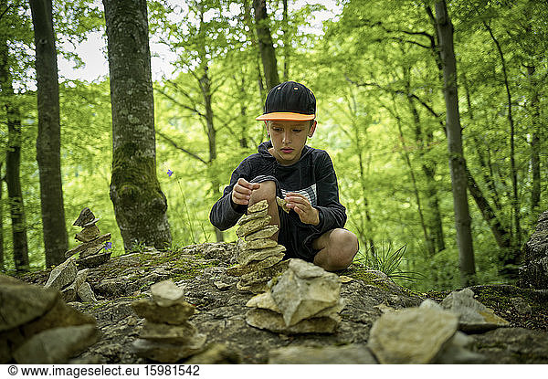 Boy stacking stones as cairn in Swabian Jura forest