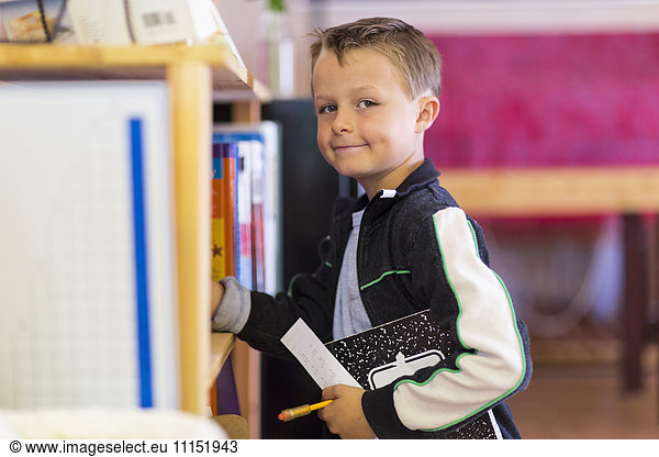 Boy standing near shelf in classroom