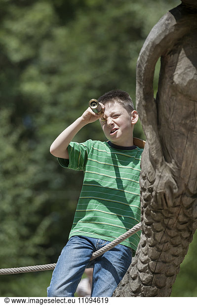 Boy standing on a ship and looking through a telescope in adventure playground  Bavaria  Germany