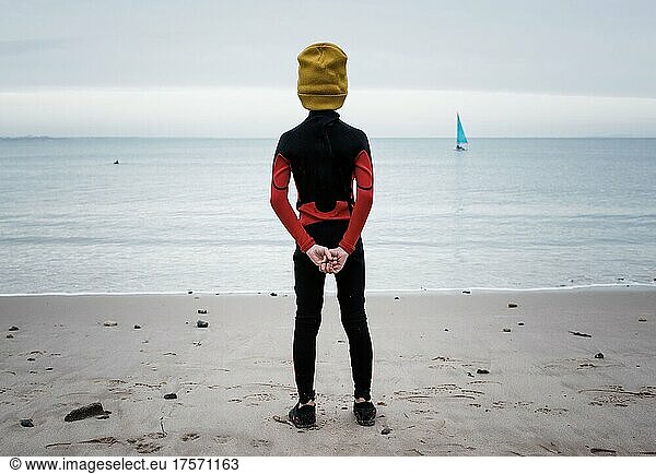boy stood looking at the ocean getting ready for cold water swimming