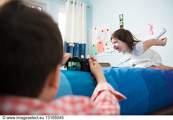 Boy taking pictures of sister play acting
