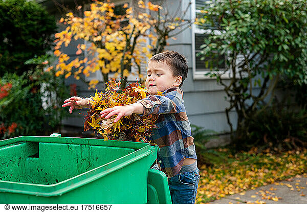 Boy throwing leaves into yard waste bin