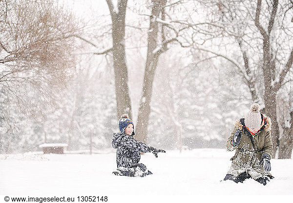 Boy throwing snowball at sister