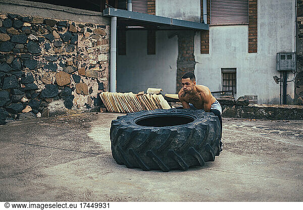 Boy training bodybuilding while pushing a tractor wheel