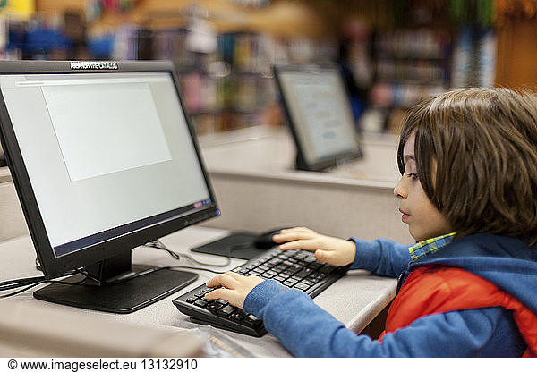 Boy using desktop computer in library