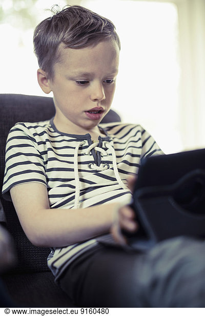 Boy using digital tablet on sofa