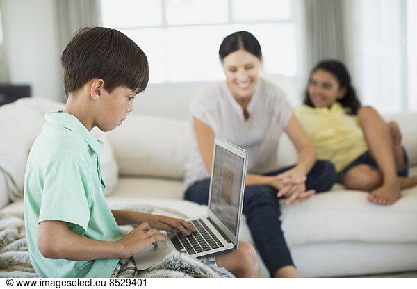 Boy using laptop on sofa in living room