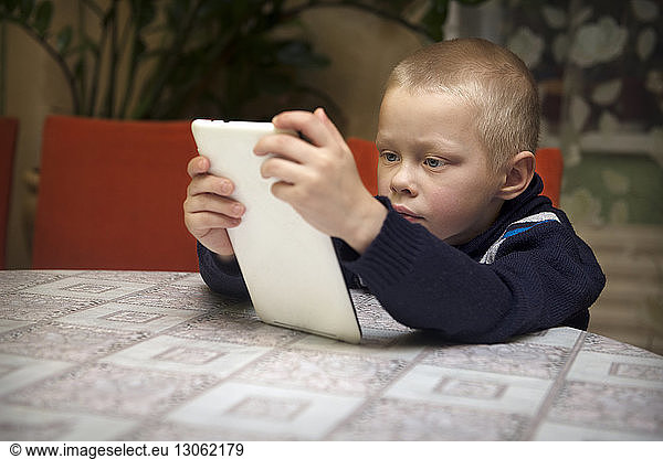 Boy using tablet computer while sitting at table