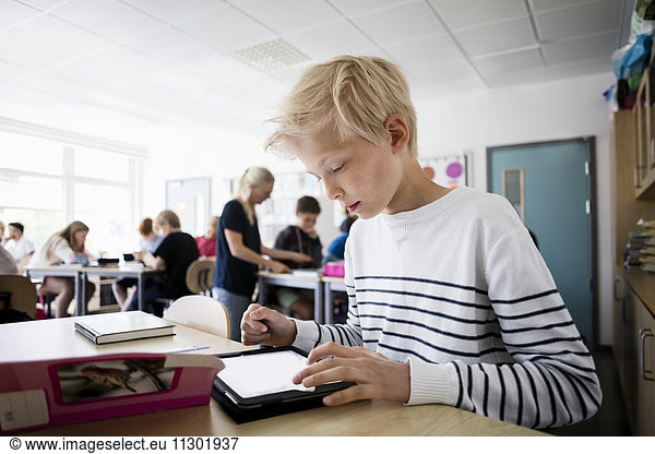 Boy using tablet pc at desk in classroom