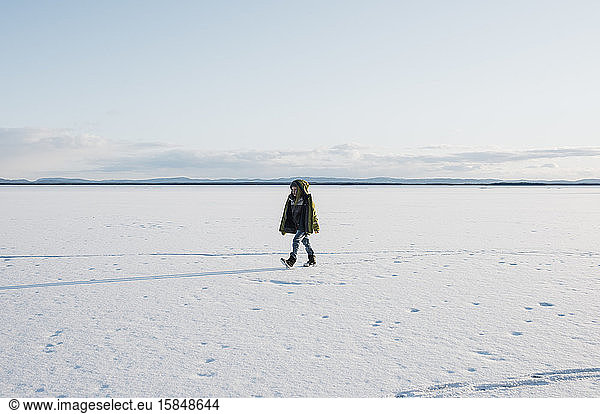 boy walking across a frozen lake alone in Sweden