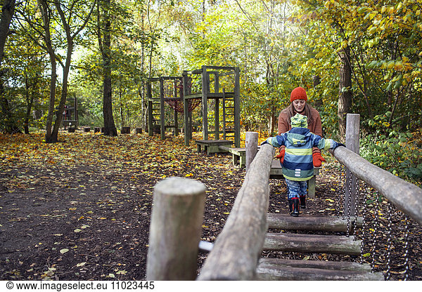 Boy walking towards mother during obstacle course in forest
