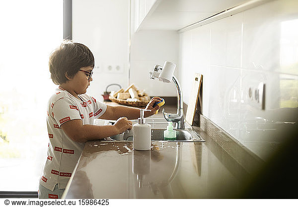 Boy washing dishes at home