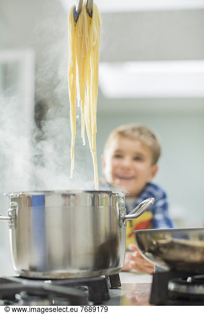 Boy watching parent cook spaghetti