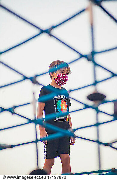 Boy wearing a mask playing alone at a playground