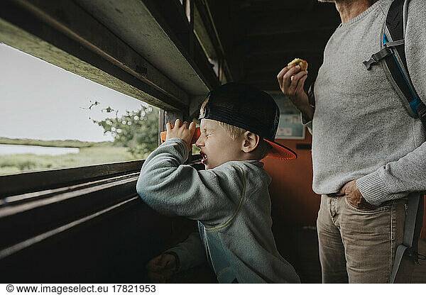 Boy wearing cap looking through binoculars