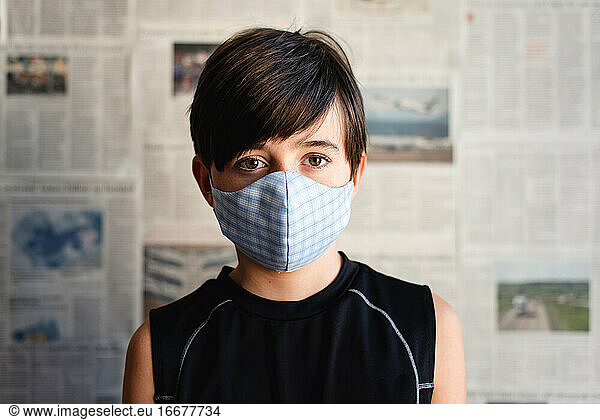 Boy wearing cloth mask against Covid 19 newspaper clippings.