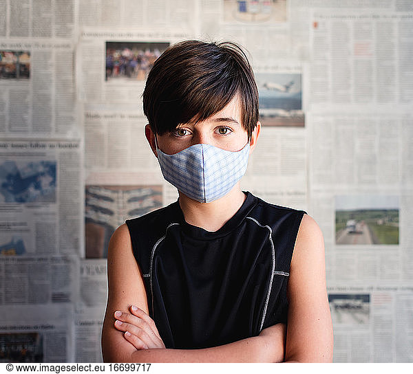 Boy wearing cloth mask against Covid 19 newspaper clippings.
