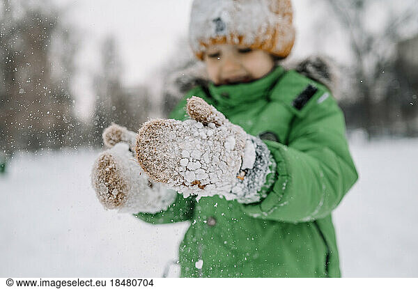 Boy wearing gloves playing with snow