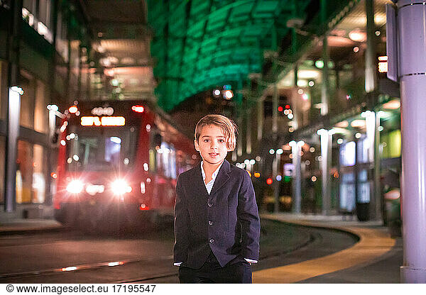 Boy wearing suit standing at train station in Downtown.