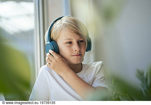 Boy wearing wireless headphones listening to music at home