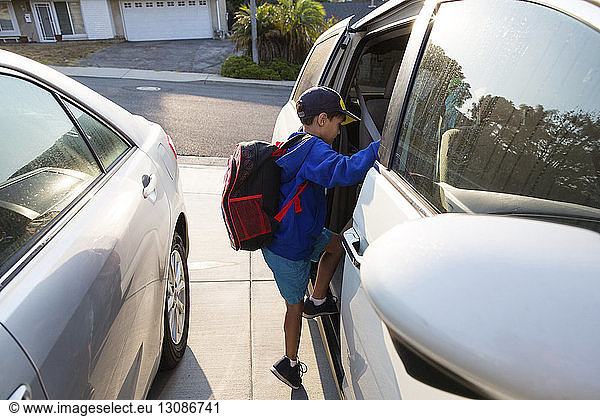 Boy with backpack entering car