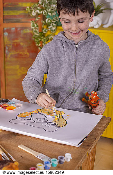Boy with brush painting a tiger at home.