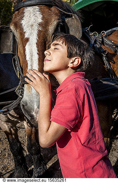 Boy with closed eyes hugging a horse