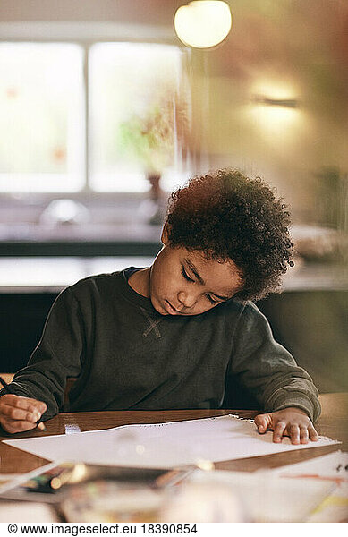 Boy with curly hair doing homework at home