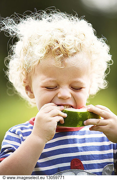 Boy with curly hair enjoying watermelon
