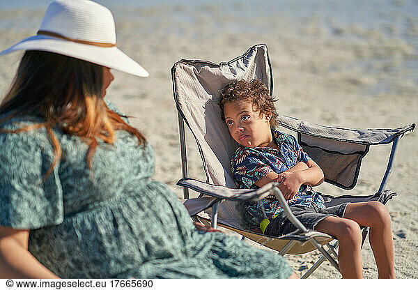 Boy with Down Syndrome in beach chair looking at mother