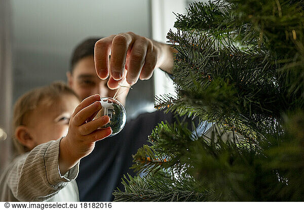 Boy with father decorating Christmas tree at home