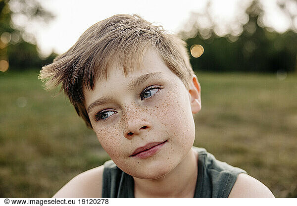 Boy with freckles day dreaming in playground