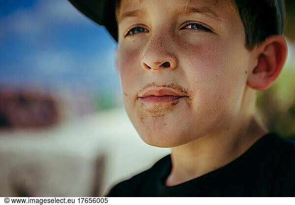 Boy with freckles has chocolate ice cream all over face