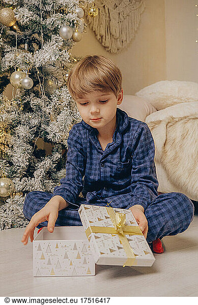 Boy with gifts under the christmas tree wearing pajama