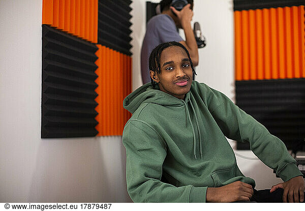 Boy with green hoodie sitting in recording studio