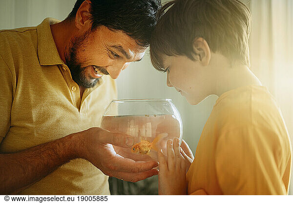 Boy with happy father holding fishbowl